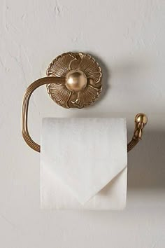 a gold toilet paper holder on a white wall