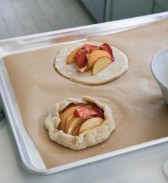 two uncooked fruit pies sitting on top of a cookie sheet