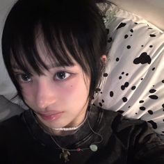 a woman laying on top of a bed wearing a black shirt and white polka dot pillow