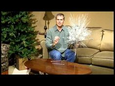 a man sitting in front of a christmas tree holding a bunch of white snowflakes