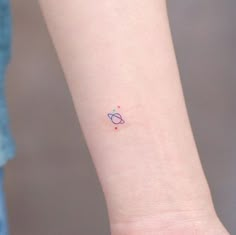 a small tattoo on the wrist of a woman's left arm, with an object in the background