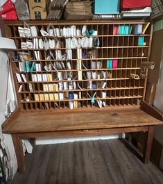 an old wooden desk with lots of papers on it and some boxes stacked up against the wall