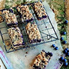 blueberry crumb bars on a cooling rack with fresh blueberries scattered around them