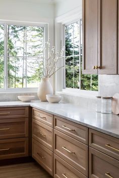 a kitchen with wooden cabinets and white marble counter tops in front of a large window