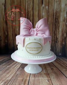 a white and pink cake with a bow on top