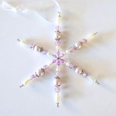 a snowflake ornament with pink and white beads