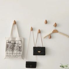 three purses hanging on the wall with wooden pegs and clothes pins attached to them