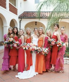 a group of women standing next to each other holding bouquets in front of a building