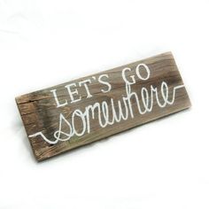 a wooden sign that says let's go somewhere on the side of a white background