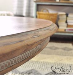 a wooden table sitting on top of a rug in front of a book shelf filled with books