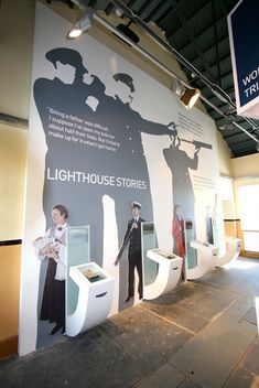 an exhibit with posters on the wall and people standing in front of urinals