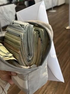 a person holding a bag full of money in their left hand, with the bottom half open