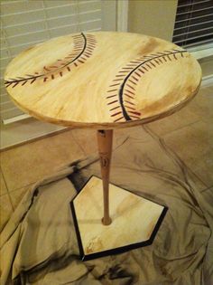 a wooden table with baseballs painted on the top and bottom, sitting in front of a window