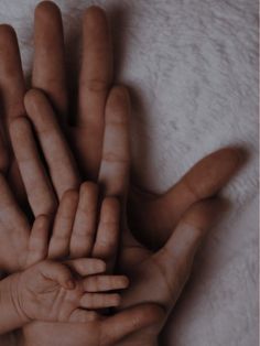 a group of hands that are on top of a white blanket with one hand extended up to the other