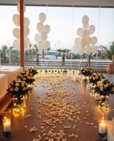 a table topped with lots of flowers and candles next to large balloons that say happy new year