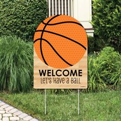 a welcome sign with a basketball on it in front of some grass and bushes,