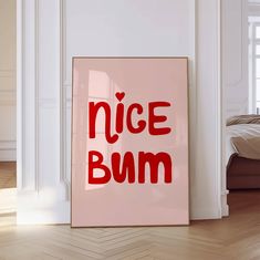 a pink framed poster with the words nice bum on it in red ink against a white wall