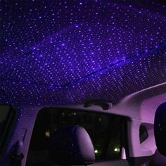 the interior of a car with purple stars on the ceiling and lights in the back