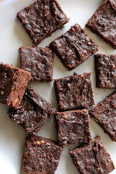 chocolate brownies cut into squares on top of a white plate, ready to be eaten