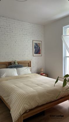 a bedroom with white brick wall and wooden bed frame in front of large window,