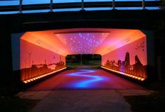 an open tunnel with lights on the sides and city skylines painted on the walls