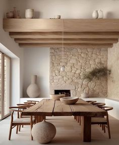 a dining room table with chairs and a bowl on it in front of a stone wall