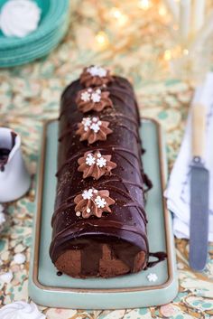 a chocolate cake with frosting and flowers on it sitting on a blue platter