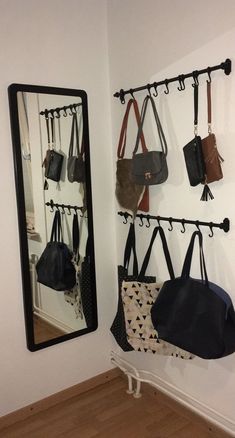 several purses hanging on the wall next to a mirror and coat rack with hooks