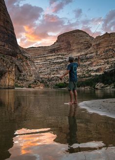 a man standing on the edge of a body of water with a kite in his hand