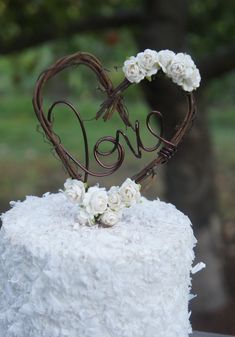 a cake with white frosting and flowers in the shape of a heart on top