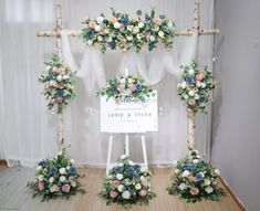 the wedding arch is decorated with flowers and greenery, along with a welcome sign