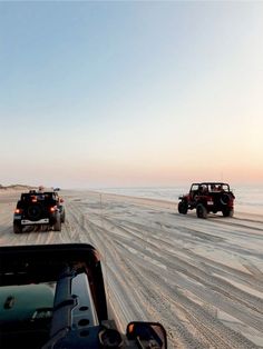 two jeeps driving down the road near the ocean