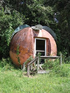 an old rusted out round structure in the middle of a field with stairs leading up to it