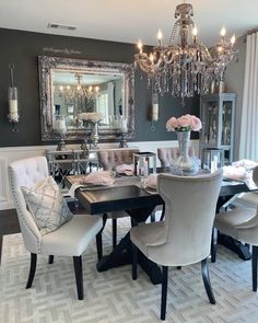 a formal dining room with chandelier, chairs and table in front of the mirror