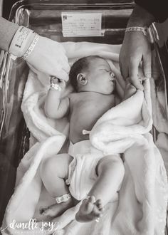 a black and white photo of a baby in a stroller being held by someone's hand