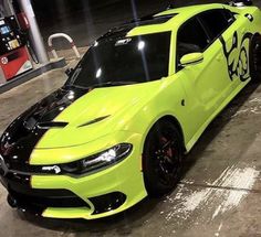 a bright yellow dodge charger parked in front of a gas station