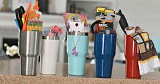 there are many different items in the cups on the counter top, including pens and pencils