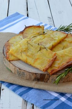 some food is sitting on top of a wooden cutting board with rosemary sprigs