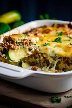 a casserole dish with zucchini, meat and cheese in it on a wooden table