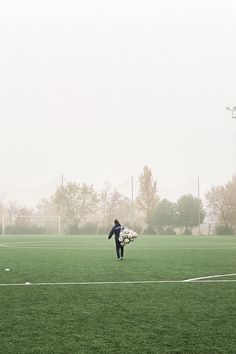 a man walking across a soccer field holding a white frisbee in his hand