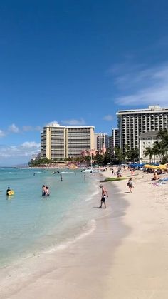 people are on the beach in front of hotels