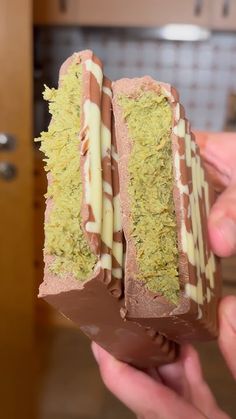 someone is holding up a chocolate sandwich with green toppings