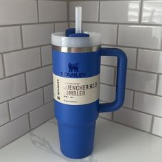 a blue travel mug sitting on top of a counter next to a white tiled wall