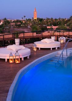 an outdoor swimming pool with chaise lounges next to it and the city in the background