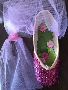 a pair of purple shoes with pink flowers and green leaves in them on a wooden surface