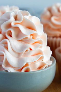 two cupcakes with white frosting in a blue bowl on a wooden table