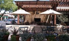 an outdoor restaurant with tables and umbrellas on the outside, surrounded by potted plants