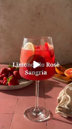 a glass filled with liquid sitting on top of a table next to sliced strawberries