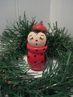 a red and black figurine sitting on top of a green wreath