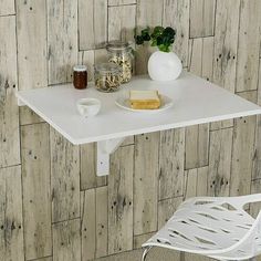 a small white table with a plate of food on it next to a glass vase